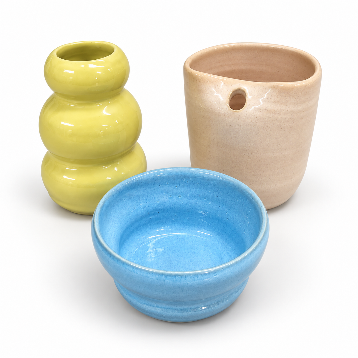 Handgemachte bunte Keramik aus einem Töpferkurs bei Studio Amun in Hamburg – gelbe Vase, blaue Schale und roséfarbenes Gefäß.